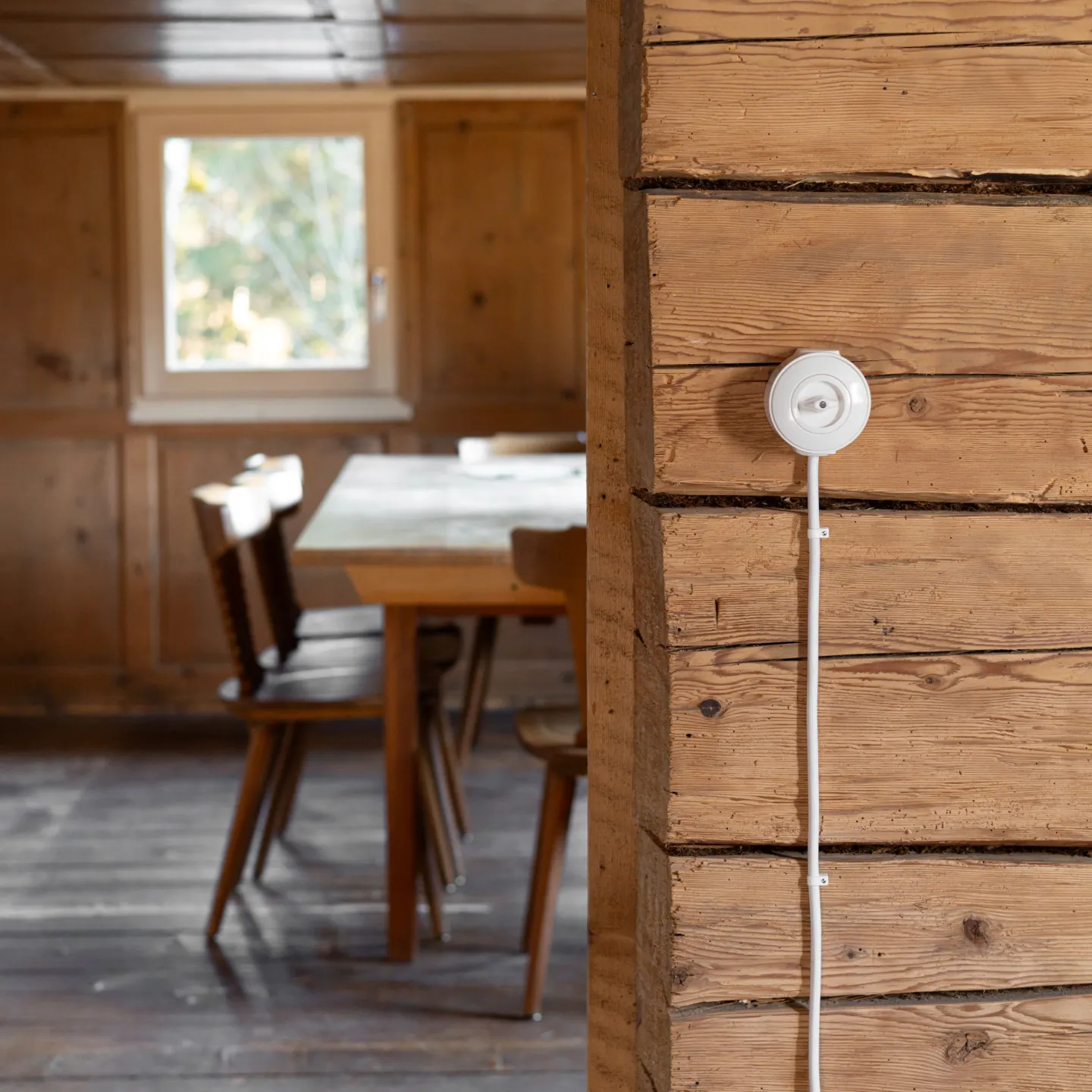 Ein weisser Lichtschalter an einer Altholzwand