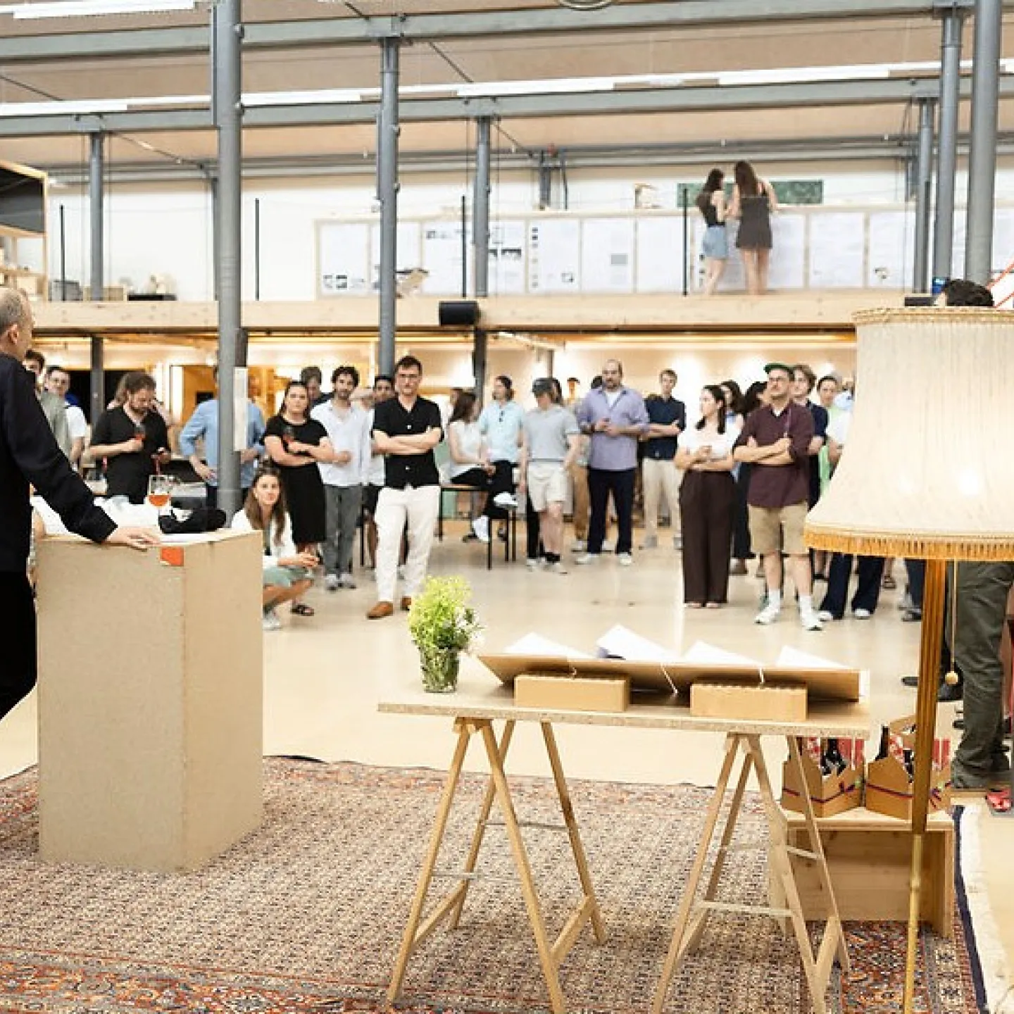 Publikum hört Mann mit Mikrofon in einem grossen Atelier zu 