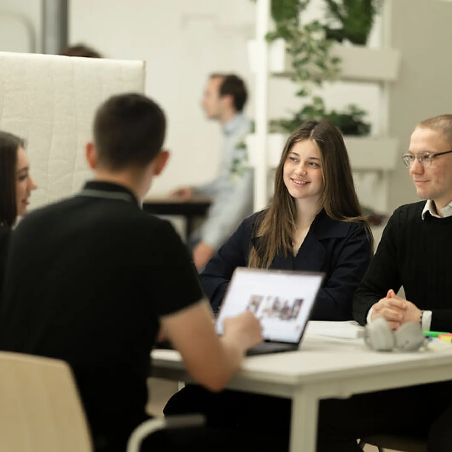 vier Personen sitzen am Tisch und besprechen etwas