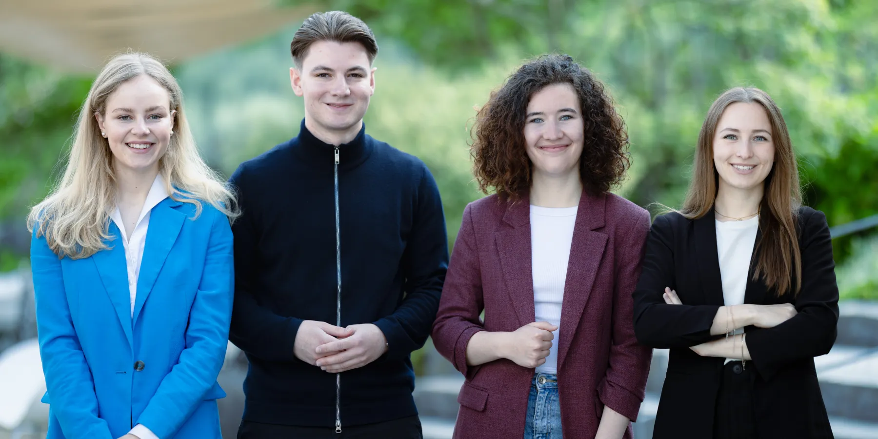 Vier Studierende der Universität Liechtenstein Bachelor BWL posieren gemeinsam im modernen Campusgebäude – Fokus auf studentische Vielfalt und Gemeinschaft.