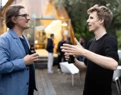 Zwei Männer stehen draußen und unterhalten sich 