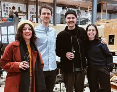 Vier Studierende in kreativer Lernumgebung des Architekturstudios lächeln in die Kamera bei lockerer Atmosphäre