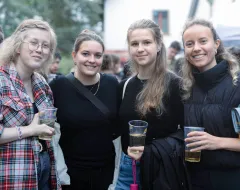Vier Studentinnen mit Getränken bei einer Outdoor Veranstaltung auf dem Campus der Universität Liechtenstein