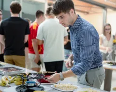 Student steht auf dem Campus der Universität Liechtenstein am Buffet während der Welcome Days