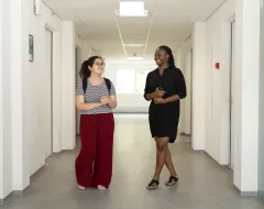 Zwei Studierende im Wohnheim der Universität Liechtenstein unterhalten sich im hellen Flur.