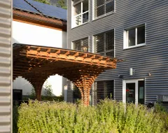 Eingang des Studierendenwohnheims der Universität Liechtenstein mit markanter Holzpergola.