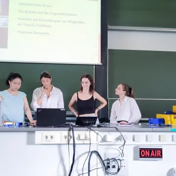 Vier Studentinnen der Universität Liechtenstein halten gemeinsam eine Präsentation zu kunsthistorischen Themen im Hörsaal.