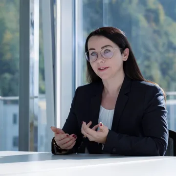 Gesprächsszene mit einer Expertin im Businessoutfit im lichtdurchfluteten Besprechungsraum der Universität Liechtenstein