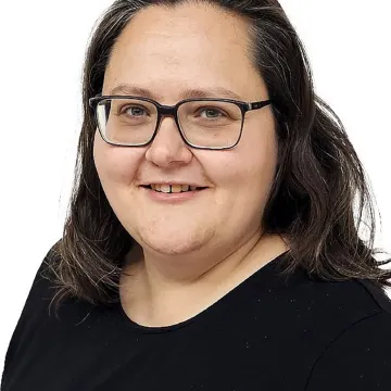 Porträt einer Frau mit Brille und schwarzen Haaren vor weißem Hintergrund an der Universität Liechtenstein.