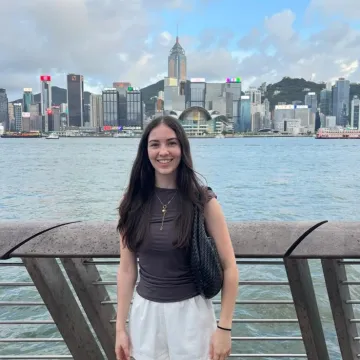 Studentin der Universität Liechtenstein vor Skyline am Wasser während Auslandsaufenthalt