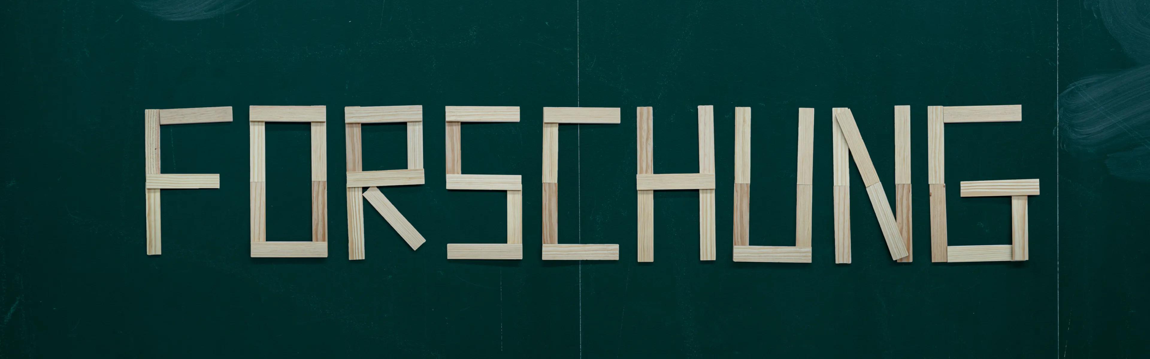 Tafel mit dem Wort Forschung aus Holzbuchstaben, umgeben von den Begriffen Innovation, Nachhaltigkeit, Digitalisierung und Verantwortung an der Universität Liechtenstein.