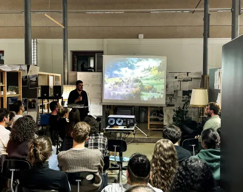 Vortragender in einem Atelier vor vielen Studierenden