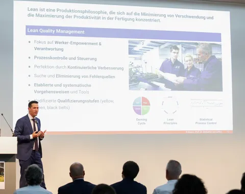 Foto von Assoz. Prof. Dr. Benjamin van Giffen während seiner Antrittsvorlesung an der Universität Liechtenstein mit dem Titel 'Tradition trifft Technologie' vor einem Publikum, darunter Rektor Dr. Christian Frommelt und andere Würdenträger.