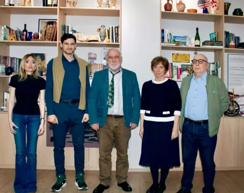 Gruppe von fünf Personen stehen vor einem Bücherregal.