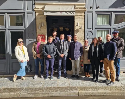 Eine Gruppe von Studierenden und Dozenten des Executive Master of Laws (LL.M.) im Wirtschaftsstrafrecht steht vor einem Gebäude in Straßburg während ihrer Studienreise zum Europarat. Sie lächeln in die Kamera und tragen verschiedene Freizeit- und Businesskleidung.