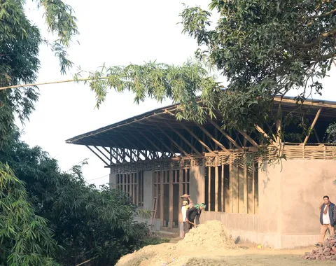 Ein im Bau befindliches Schulgebäude in Bahuarwa, Indien, umgeben von Bäumen. Das Projekt wird von Daniel Haselsberger und seiner Frau Isha initiiert und unterstützt.