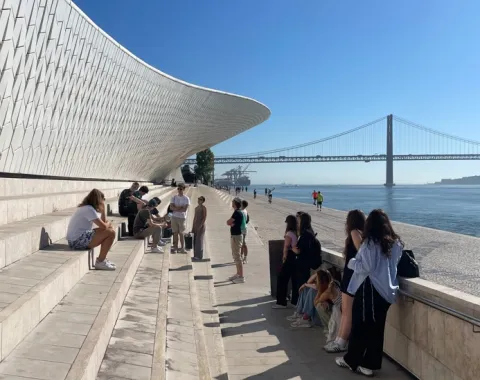 Gruppe junger Menschen sitzen auf Stufen vor einer Brücke