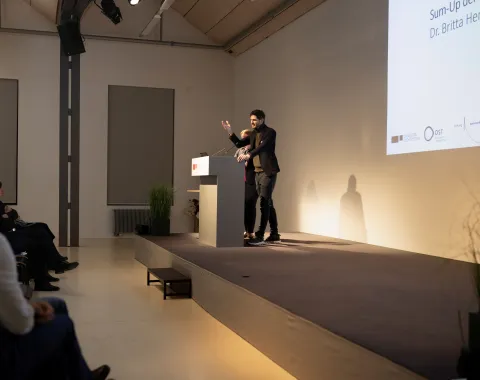 Eine vortragende Person auf einer Bühne 