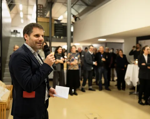 Ein Mann spricht vor einer Gruppe von Menschen in ein Mikrofon