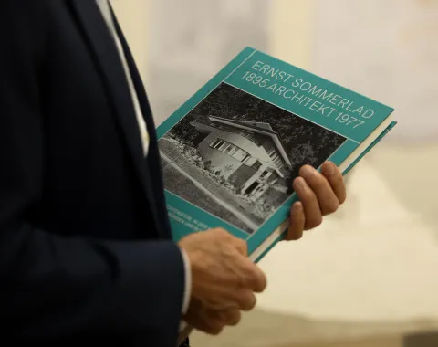 Eine Person hält ein blaues Buch mit dem Titel "Ernst Sommerlad"