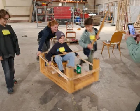 Mehrere Kinder schieben eine rollende Holzkiste