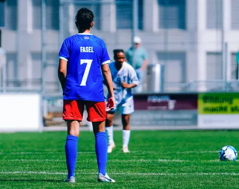 Fussballspielerin beim Anstoss auf dem Spielfeld während eines Spiels mit Gegnerin im Hintergrund