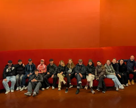 Gruppenfoto von Studierenden mit rotem Hintergrund