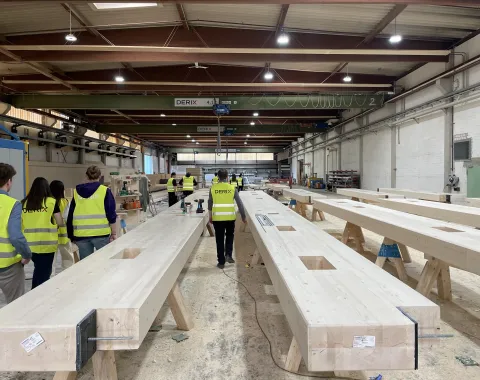 Gruppe von Studierenden läuft durch eine Produktion mit Holzelementen