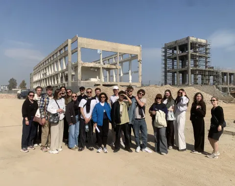 Gruppe von Studierenden schaut in die Kamera mit Betonkonstruktion im Hintergrund