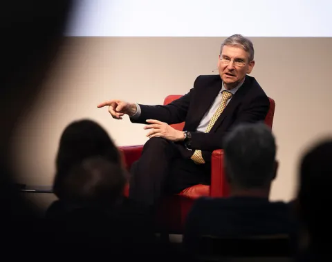 Gesprächspartner gestikuliert im roten Sessel beim Campus-Gespräch der Universität Liechtenstein
