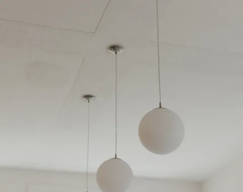 Mehrere weisse Hängeleuchten in einem weissen Raum