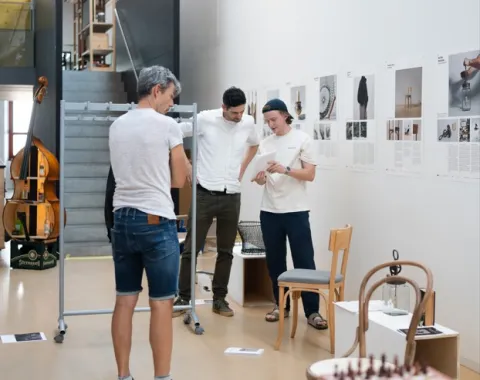 Mehrere Menschen stehen in einer Ausstellung mit Alltagsgegenständen 
