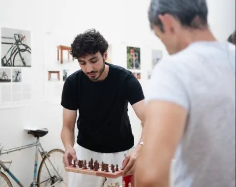 Ein Mann mit schwarzem Shirt stellt ein Schachbrett auf einen Ausstellungsbock 