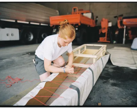 Eine junge Frau arbeitet an einem selbstgebauten Boot. 