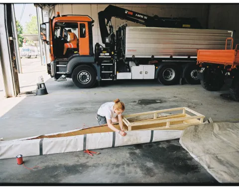 Eine junge Frau arbeitet an einem selbstgebauten Boot. 