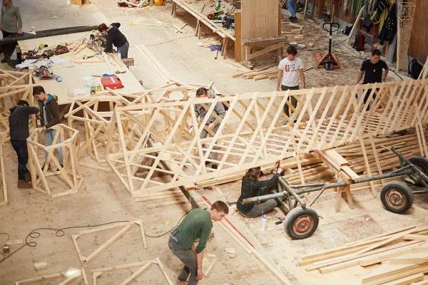Eine Holzwerkstatt wo ein Turm aus Holz von Menschen gebaut wird