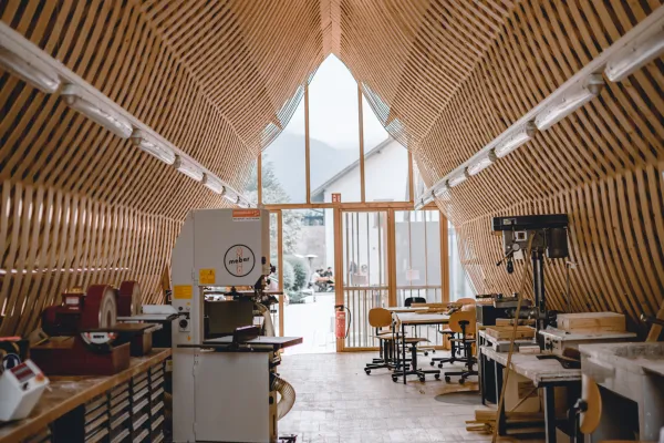 Gesamtsicht der hellen Holzwerkstatt mit Maschinen, Werkbänken und Fenstern