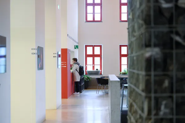 Studierende stehen im Eingangsbereich des historischen Campusgebäudes der Universität Liechtenstein mit auffälligen roten Fenstern.