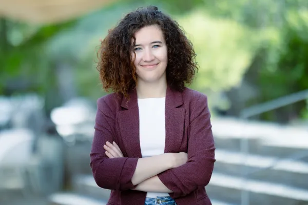 Studentin Bachelor BWL der Universität Liechtenstein im lila Jacket lächelt in die Kamera – Campusaufnahme 