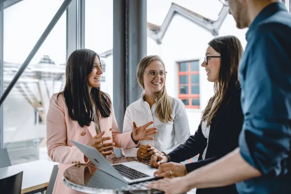Masterstudierende im Studiengang Innovative Finance der Universität Liechtenstein im Austausch bei einer Gruppenarbeit mit Laptop in moderner Lernumgebung.