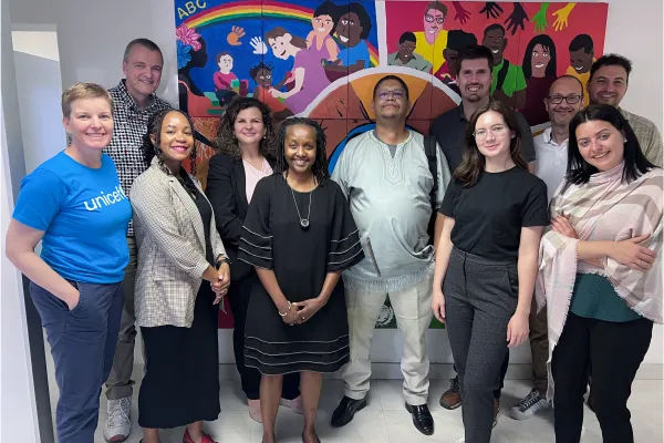 Gruppe internationaler Partnerinnen und Partner des Projekts Innovative and Digital Finance an der Universität Liechtenstein vor einem bunten Wandbild.