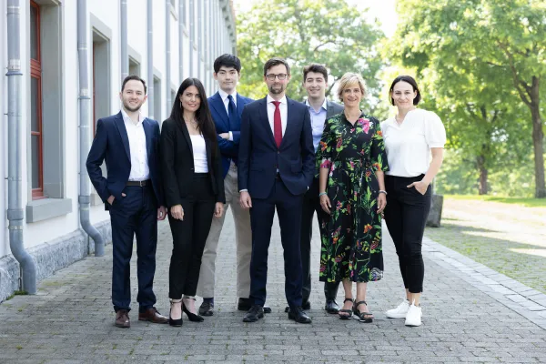 Gruppe von sieben Personen in Businesskleidung vor dem Gebäude der Universität Liechtenstein.