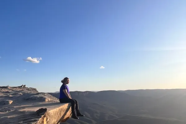Eine Studierende der Universität Liechtenstein sitzt während ihres Auslandsaufenthalts auf einem Fels über einer Schlucht