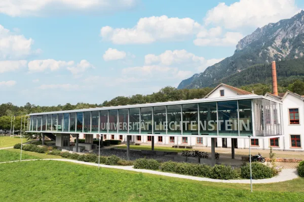 Moderne Glasfassade der Universität Liechtenstein mit Blick auf das Alpenpanorama.