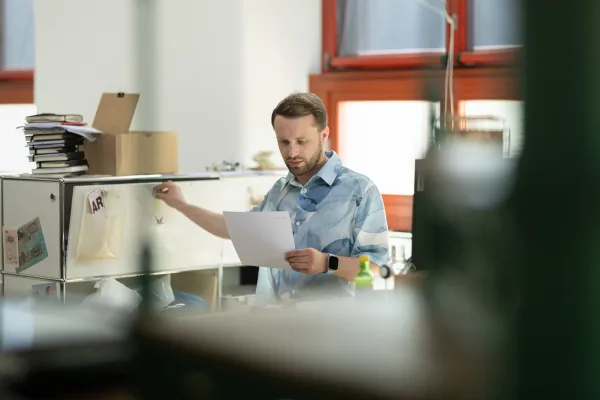 Student arbeitet im Büro an der Universität Liechtenstein und liest ein Dokument.