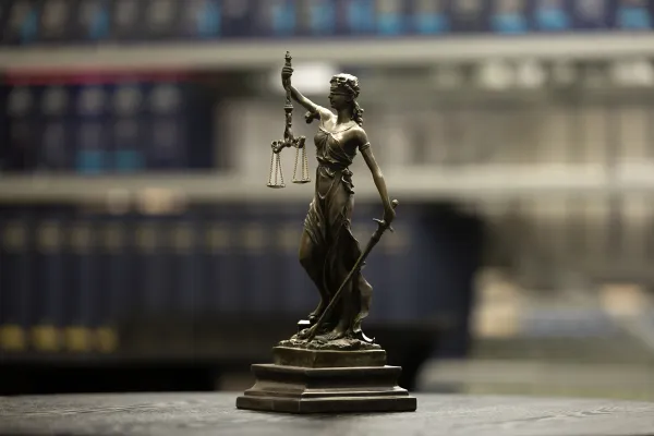 Justitia-Statue vor Bücherregalen in der Bibliothek der Universität Liechtenstein.