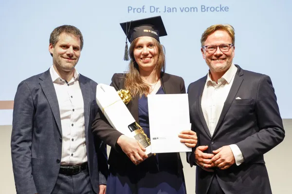 Dr. Christian Frommelt und Prof. Dr. Jan vom Brocke neben Dr. Amandine Herbé mit ihrem Diplom.