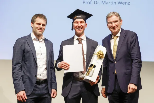 Dr. Christian Frommelt und Prof. Dr. Martin Wenz neben Dr. Kasem Zotkaj mit seinem Diplom.