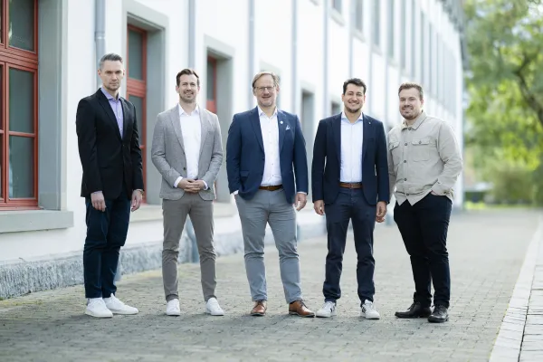 Fünf Mitglieder der Professur für Finanzökonomie stehen vor einem Gebäude der Universität Liechtenstein, business-casual gekleidet, lächelnd und nach vorne gerichtet, Symbol für Teamarbeit in Forschung und Lehre.