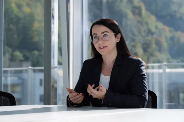 Businessporträt einer Referentin im Gespräch vor Fensterkulisse mit moderner Arbeitsumgebung